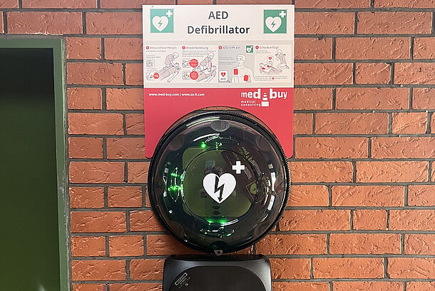 AED im runden Wandkasten im Eingangsbereich der Sporthalle